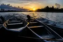 Barcos de pesca no rio ao pôr do sol em fotografia autoral de Calblima